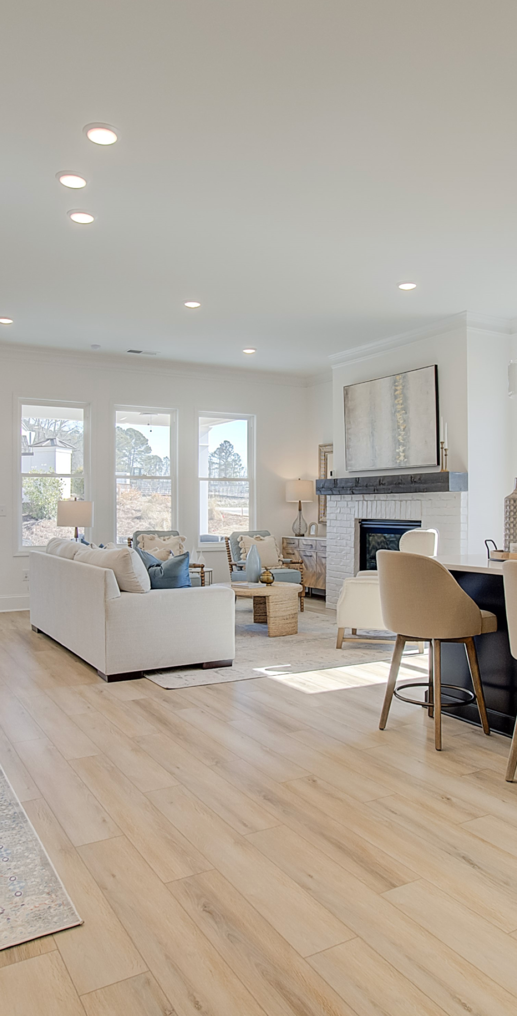 Elegant modern living room with white furniture, hardwood floors, and natural lighting